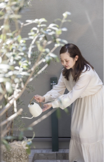 テラスのグリーンに水をあげる女性